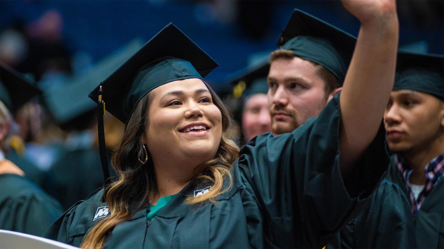 Students at commencement waving at family.